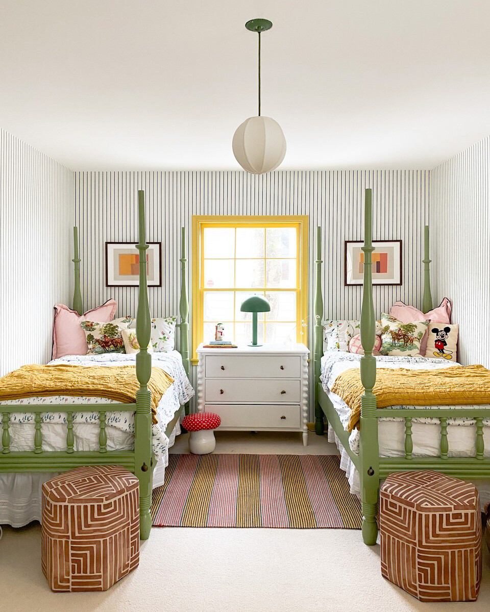 a kids' room with green four-poster twin beds, striped wallpaper, and yellow painted trim