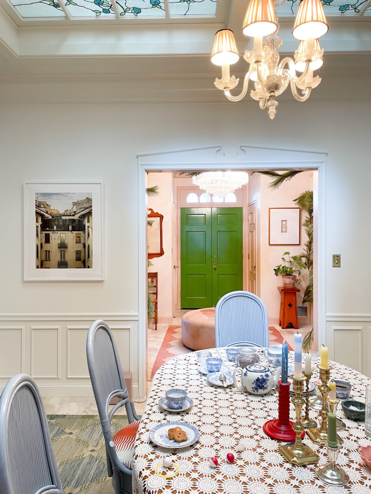 Dining room with blue secondhand chairs, Chairish rug, white walls, a large skylight, and a green front door in the distance.