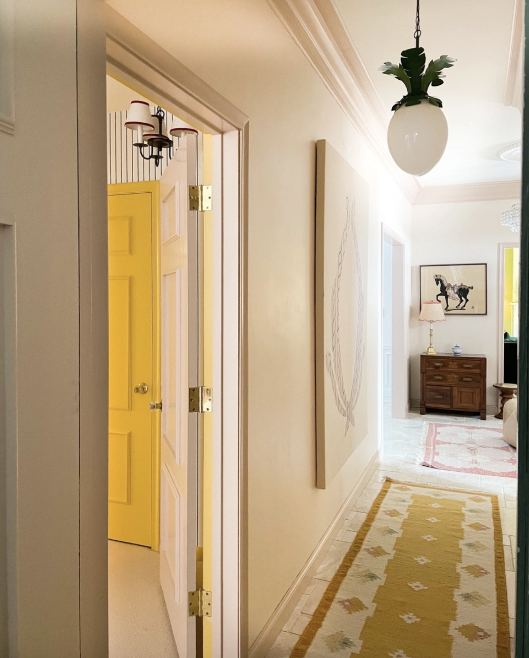 A yellow Swedish kilim runner leads from a bedroom hallway to a bright entryway