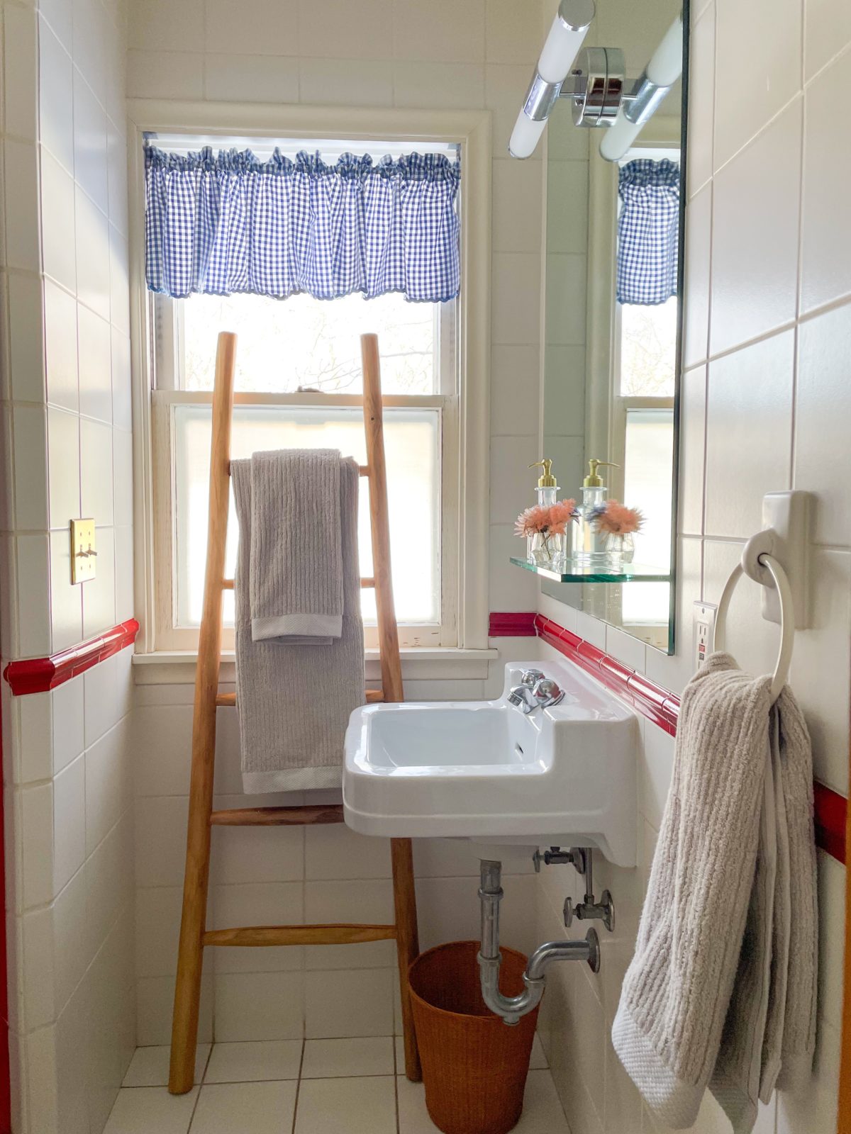 Grey organic cotton bath towel from Avocado hanging on a wooden rack. Bathroom sink and an additional towel is visible in the foreground.
