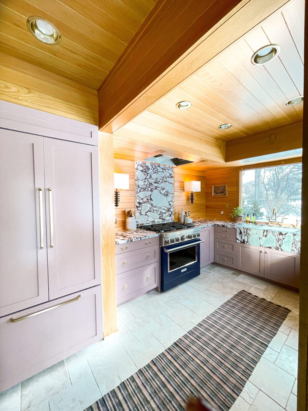 A blue oven in a kitchen. Kitchen has pink cabinets and white marble floors. 