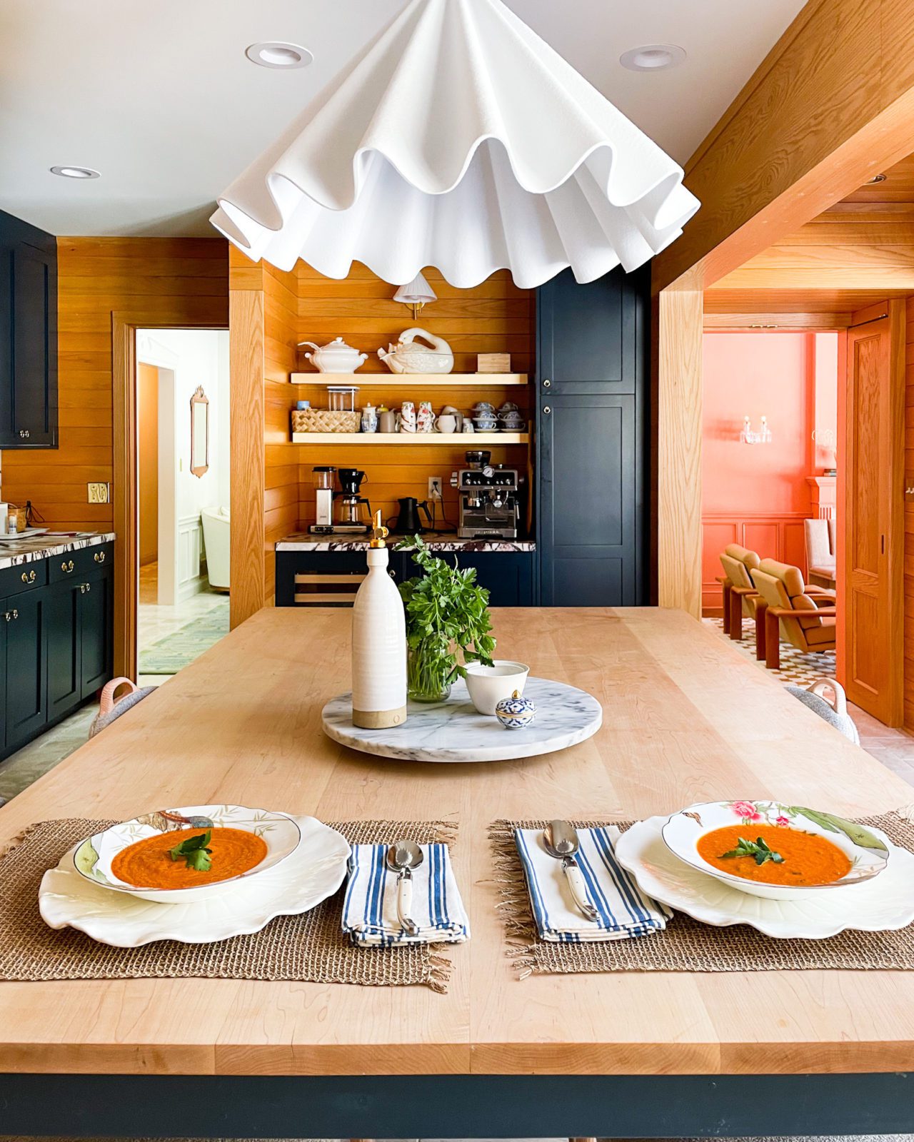 Two bowls of roasted tomato soup on a wooden table in a kitchen. 