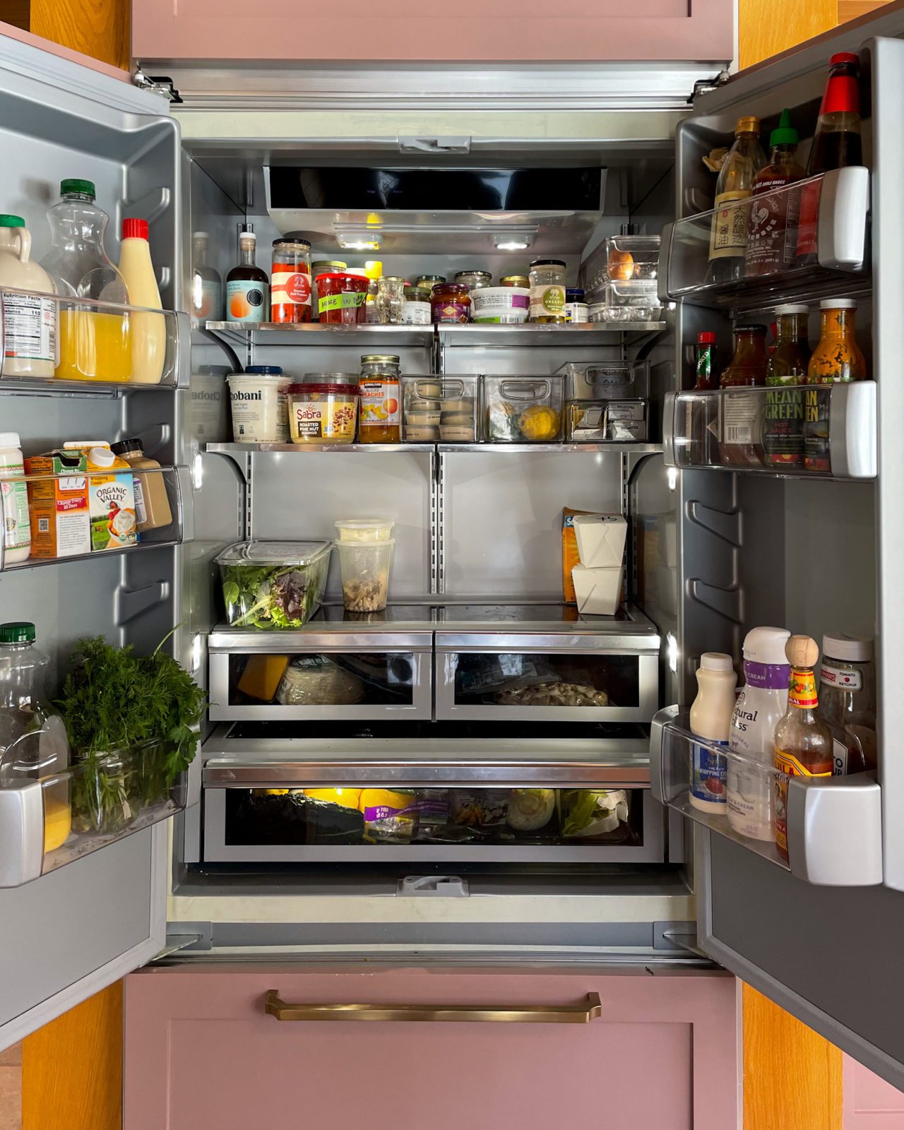 Fridge organization. An open paneled fridge stocked with food. 
