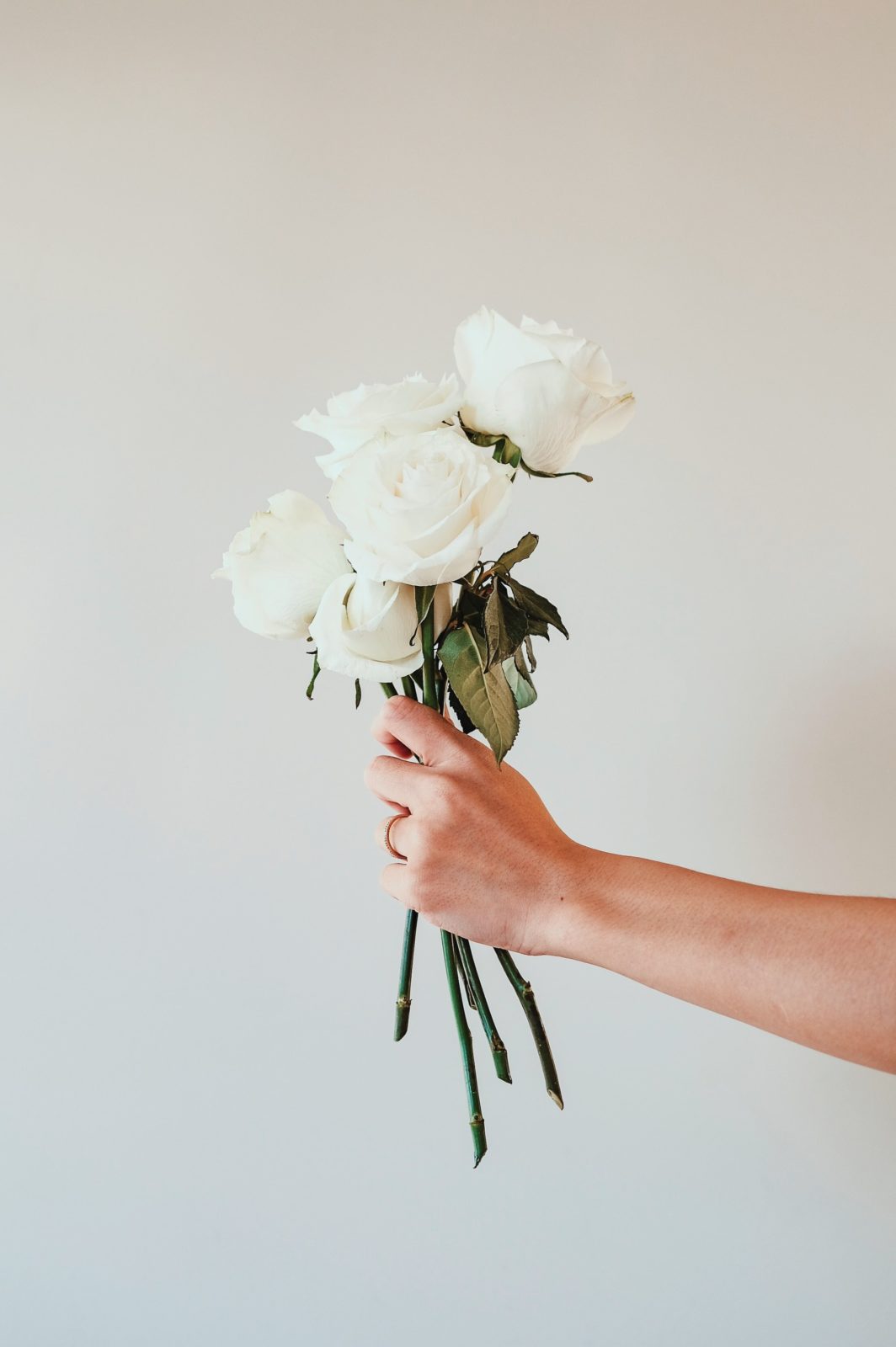 Getting married. White roses held up by a hand.