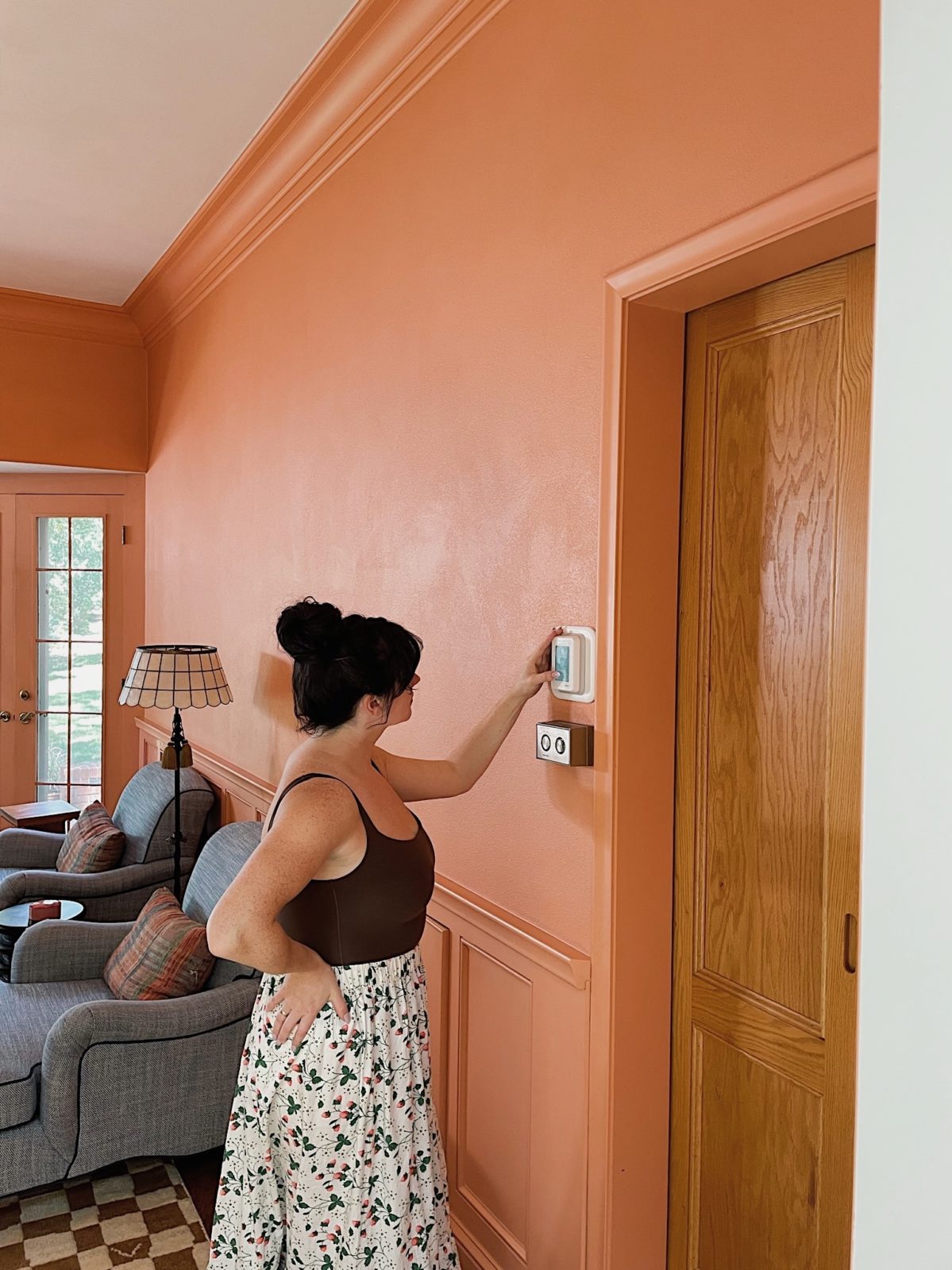 Woman in a peach room setting a thermostat