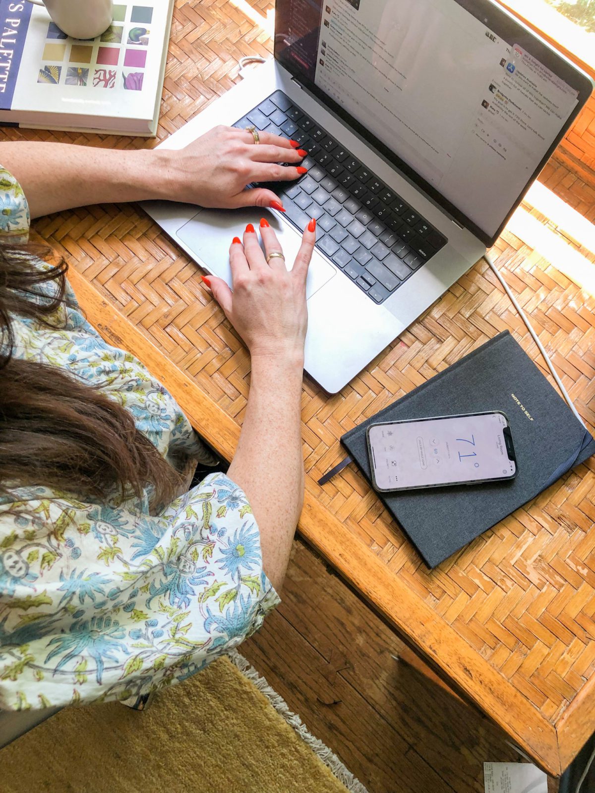 Woman working on a laptop with her smartphone next to her.