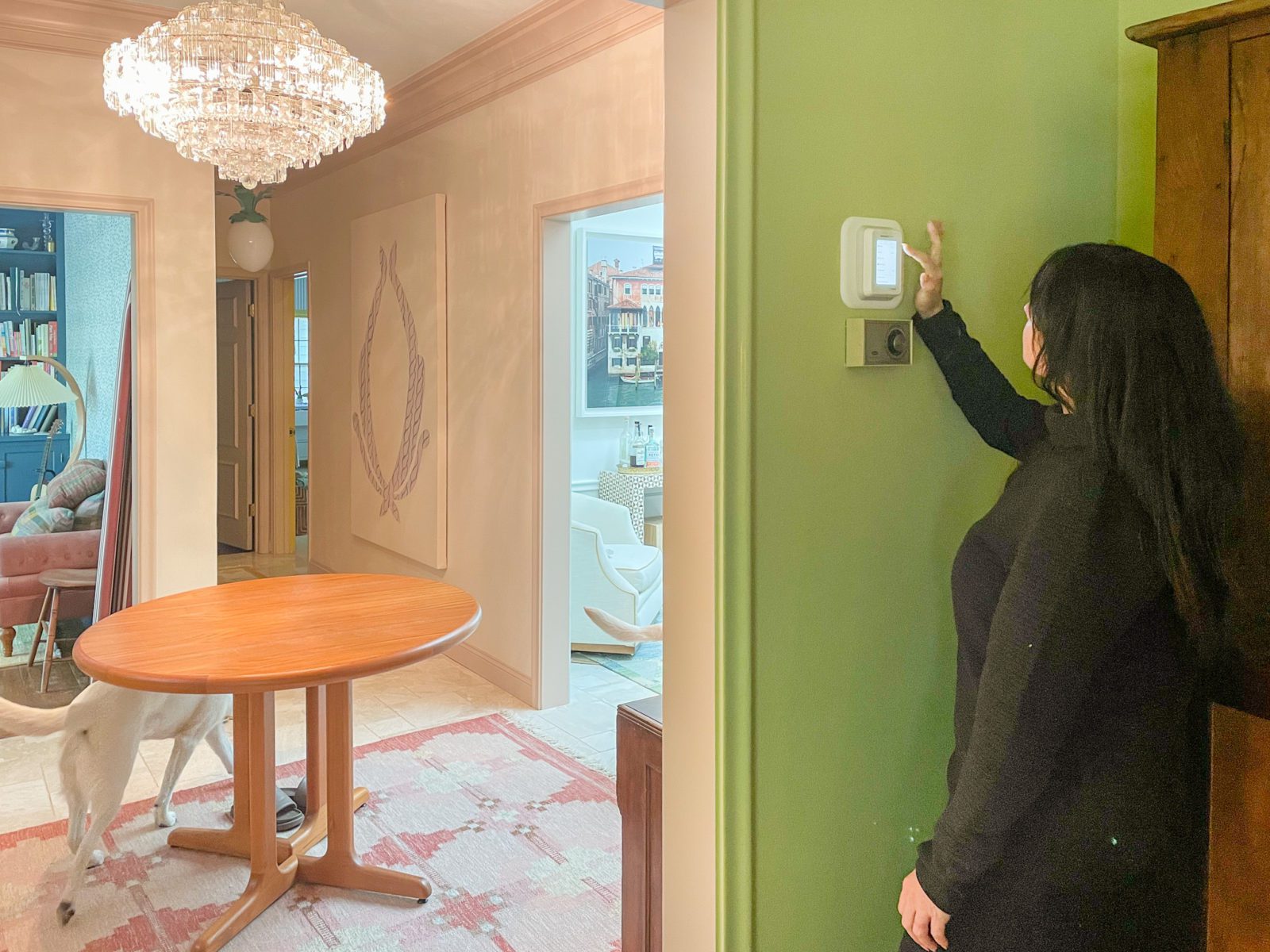 Woman adjusting her wall thermostat in the foreground.