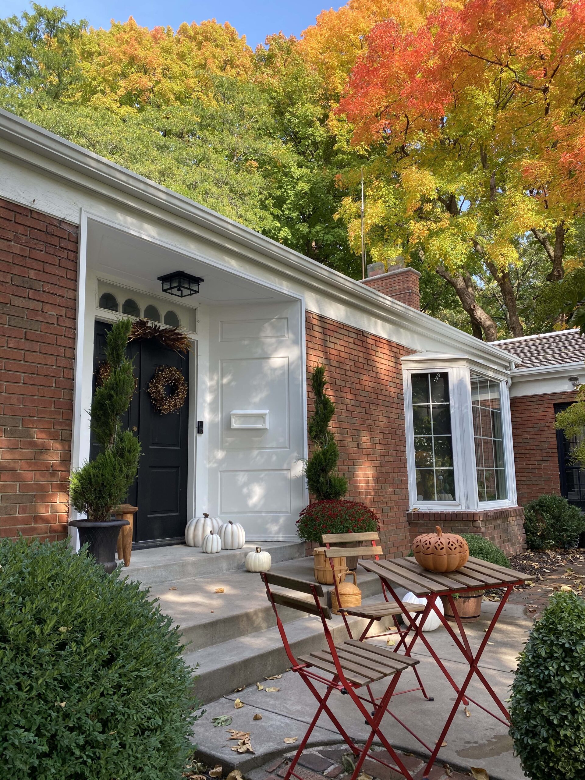 A view of a front of a house in front a landscaped fall garden.