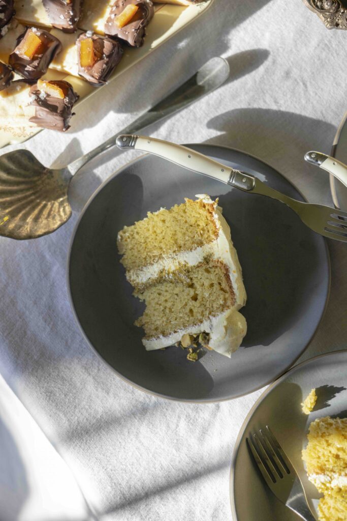 A slice of ricotta olive oil cake with pistachio butter sits on a coffee table