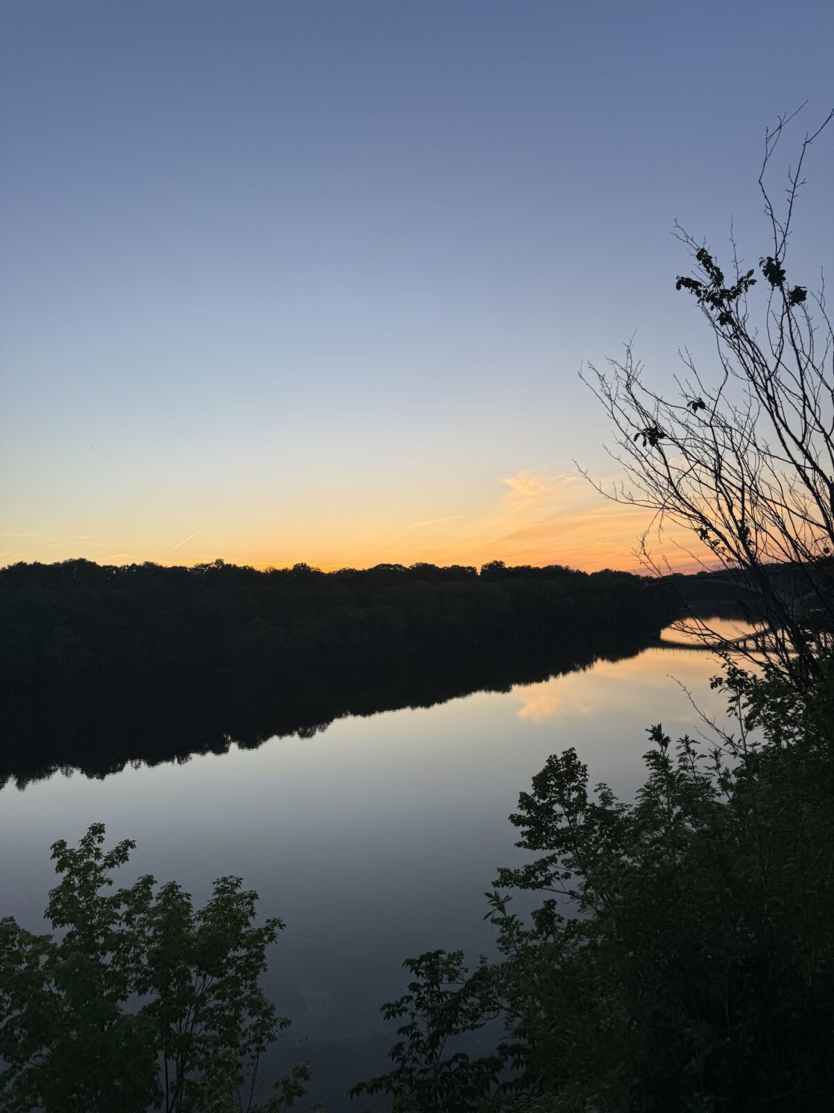Photo taken from the bank of a river at sunset
