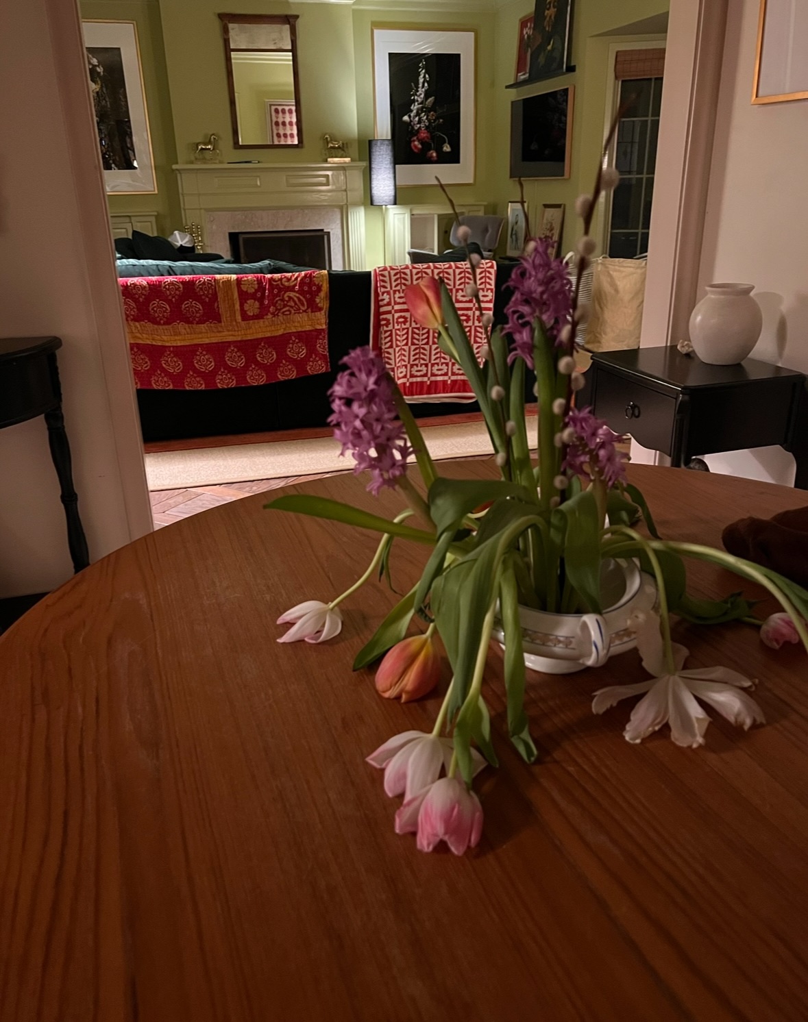 A potted assortment of flowers lazily droop over a table in an entryway