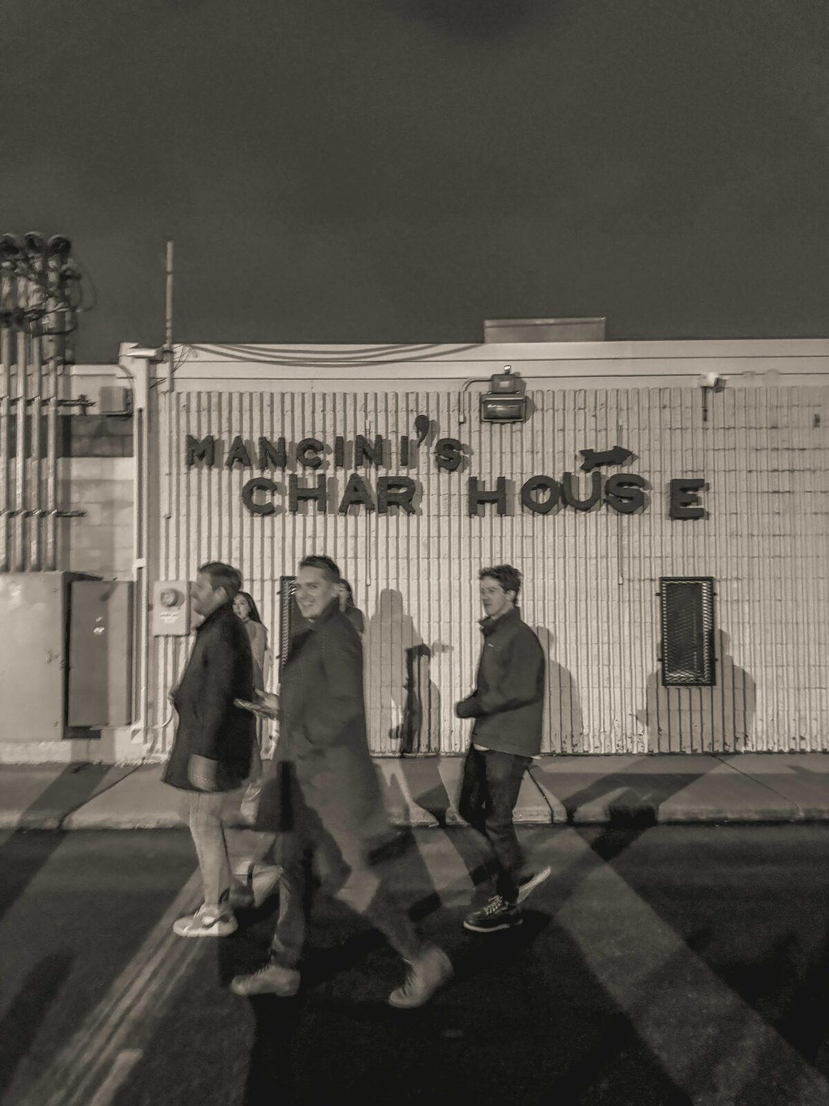A group of friends walk outside of Mancini's Char House on a winter night