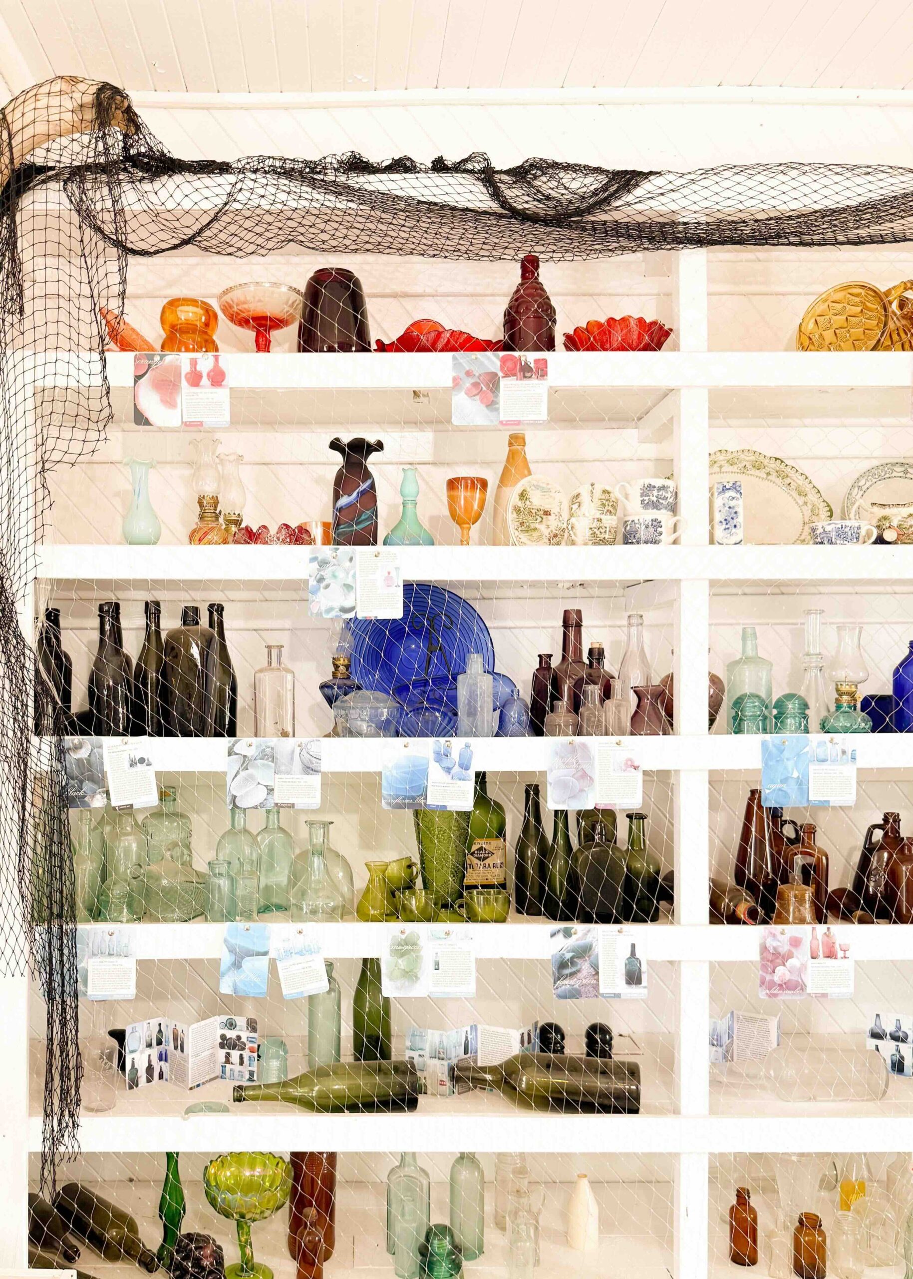 Antique glassware on a white open shelf in a Prince Edward Island gift shop