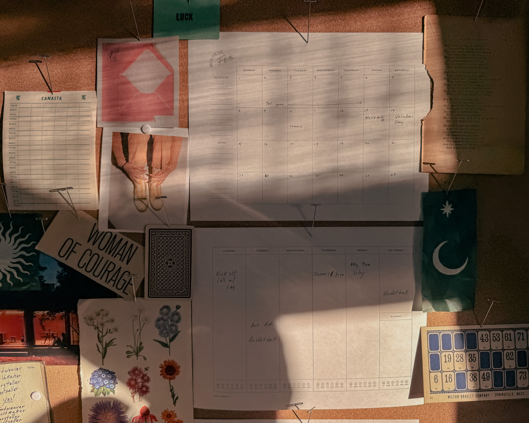 The printable Wit & Delight monthly and weekly planner pages hang on a bulletin board in a home office that's drenched in afternoon sunlight