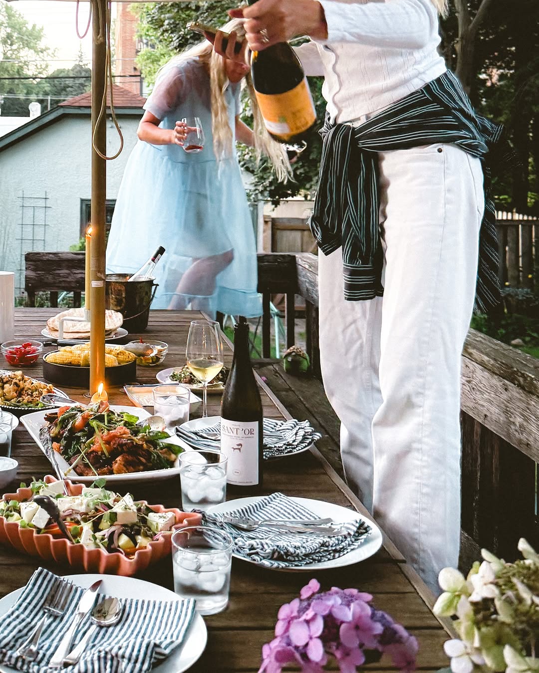 a woman takes a photo of an outdoor table setting at a summer dinner party