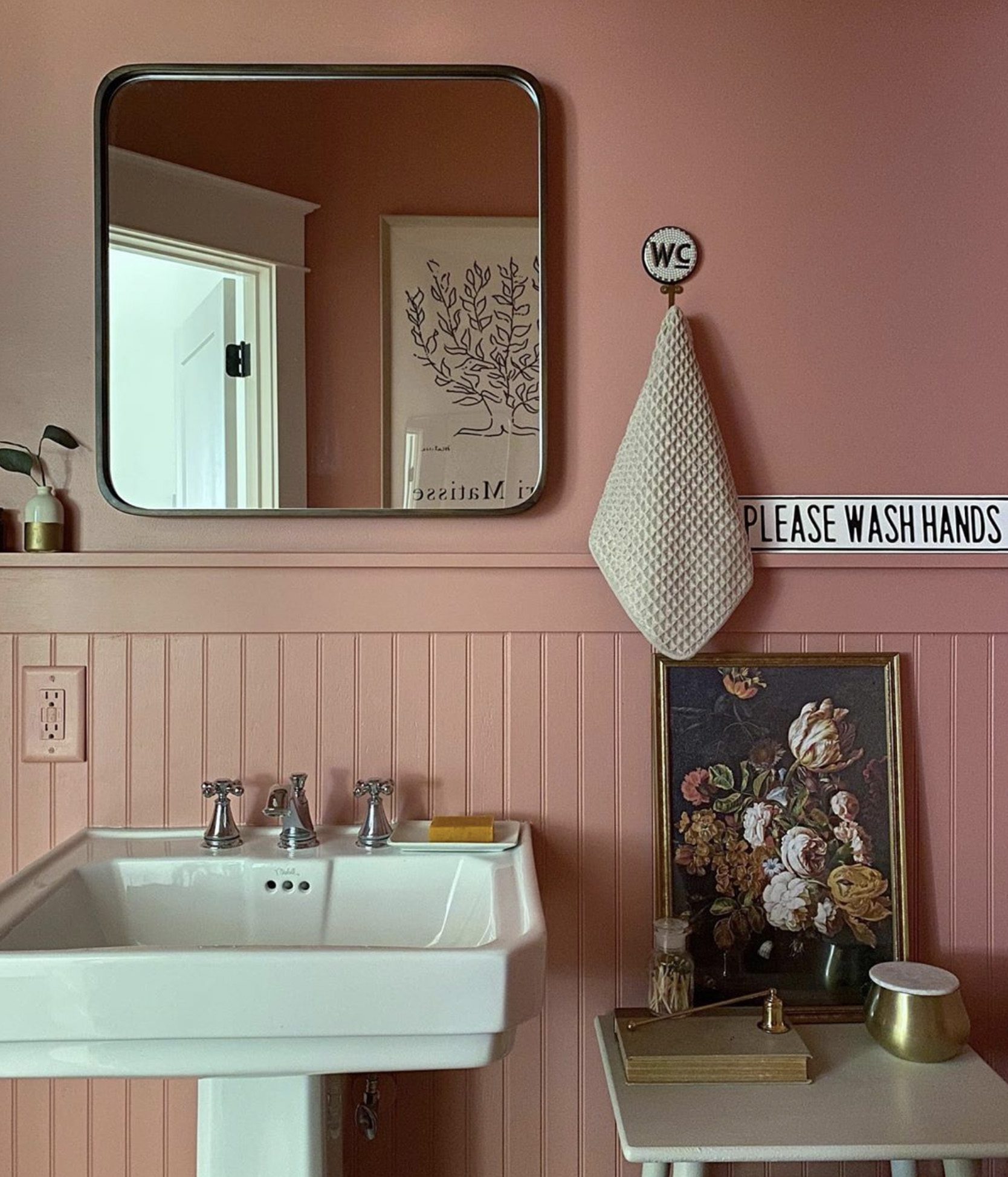 A small, pink bathroom with a white toilet and sink.