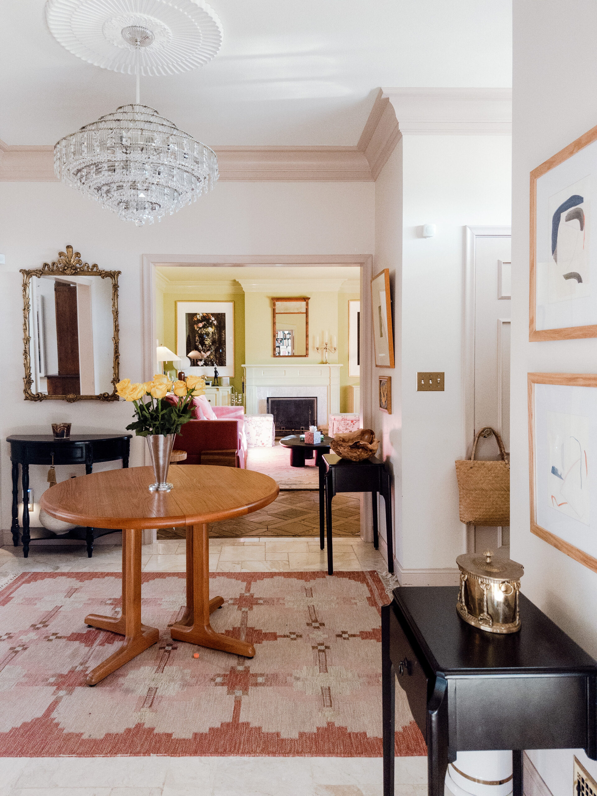 An entryway with Farrow & Ball's restored painted plaster, a chandelier from the estate, a round entry table, and a pink patterned flat weave rug.
